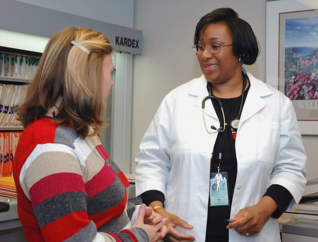 A Black female doctor listens to her patient