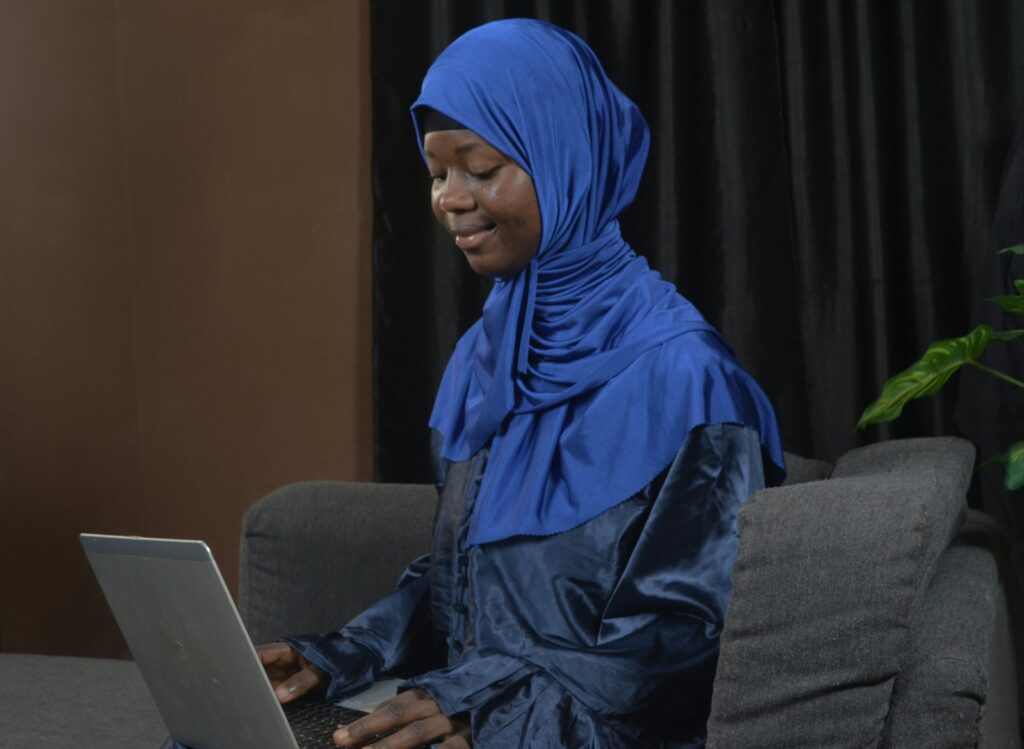 A translator in a hijab works on a laptop